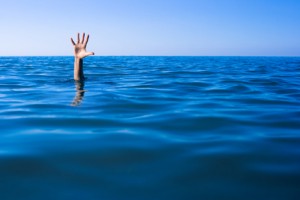 Help needed. Drowning man's hand in sea or ocean.